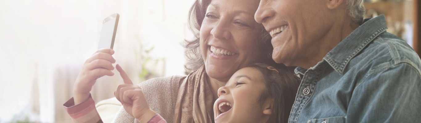 Granddaughter laughing with grandparents at phone