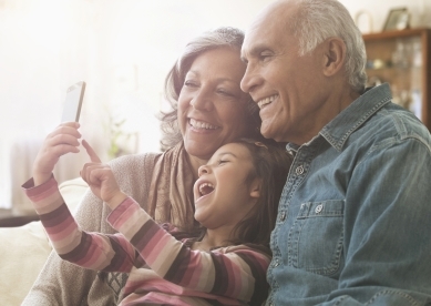 Granddaughter laughing with grandparents at phone