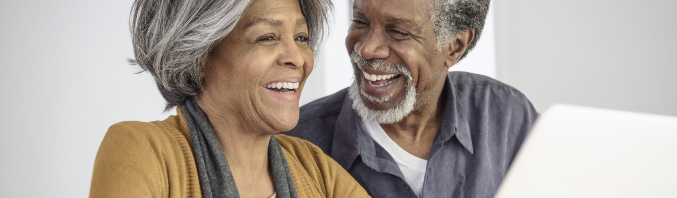 Senior Couple Laughing by Laptop